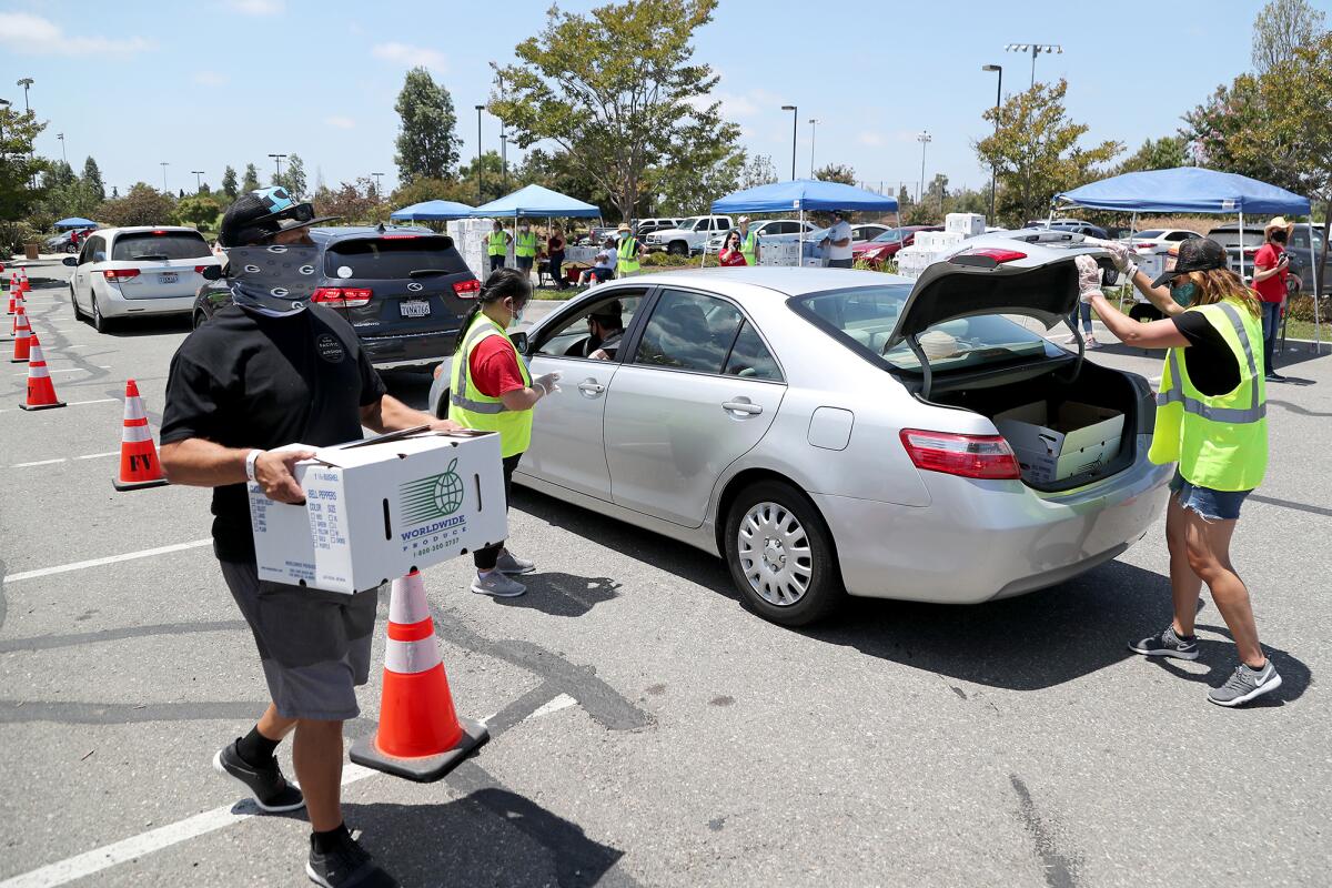 Volunteers help load Worldwide Produce pre-boxed groceries during a drive-through food giveaway.