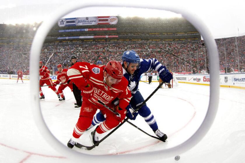 Framed by cutout in the safety glass, Red Wings right wing Daniel Cleary (71) and Maple Leafs defenseman Cody Franson (4) battle for the puck during the third period of the NHL Winter Classic at Michigan Stadium in Ann Arbor, Mich., on Wednesday.