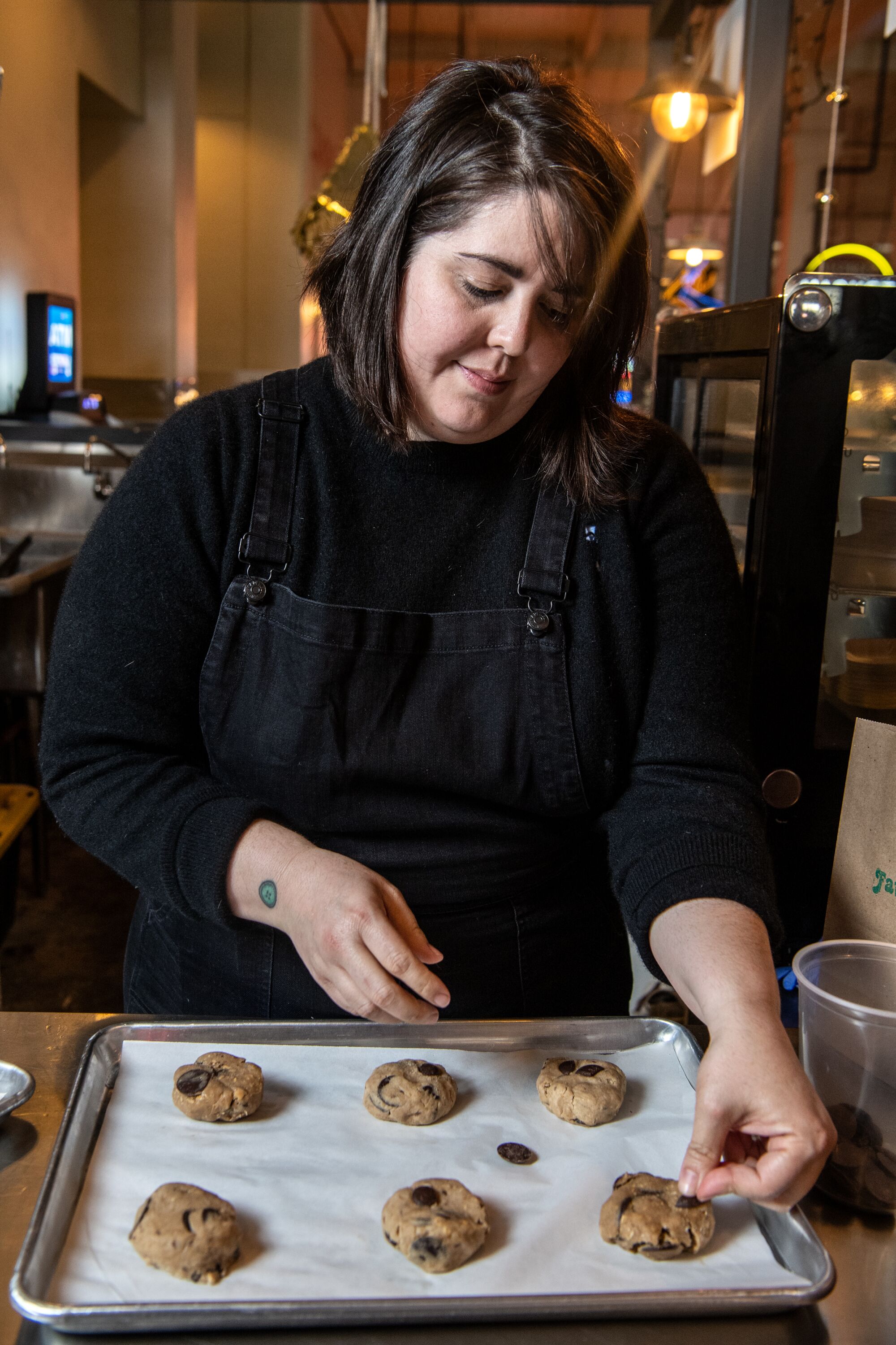 A woman working on pieces of cookie dough on a tray