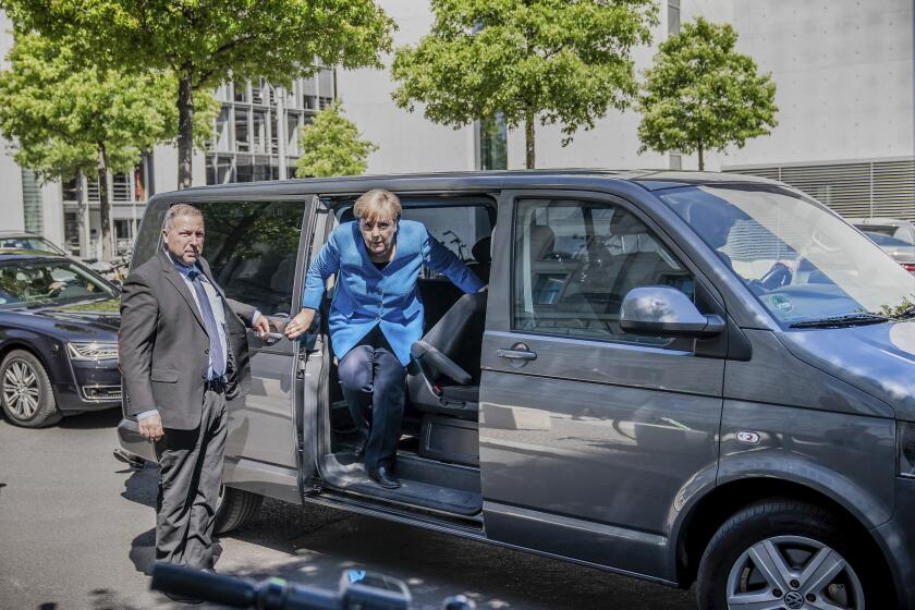 Chancellor Angela Merkel steps out of a minibus as she arrives for a parliament session at the Reichstag building in Berlin, Germany, Friday, May 29, 2020. Because of the coronavirus crisis the Merkel is chauffeured in a minibus in order to keep the distance rules. (Michael Kappeler/dpa via AP)