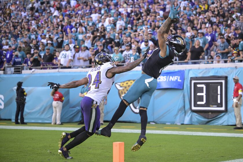 El receptor de los Jaguars de Jacksonville atrapa el balón para un touchdown mientras lo defiende el cornerback de los Ravens de Baltimore en el encuentro del domingo 27 de noviembre del 2022. (AP Foto/Phelan M. Ebenhack)