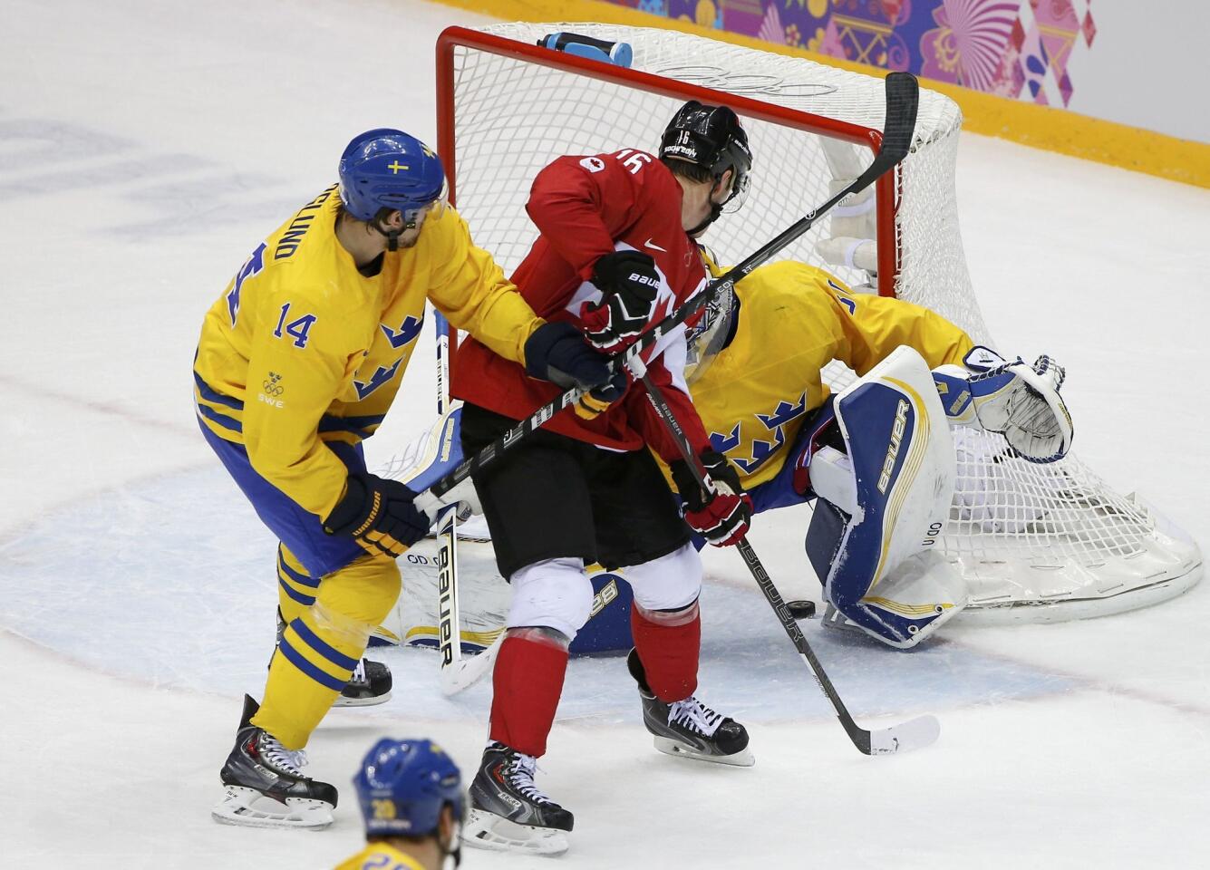 Canada's Jonathan Toews scores on Sweden's goalie Henrik Lundqvist as Sweden's Patrik Berglund defends.