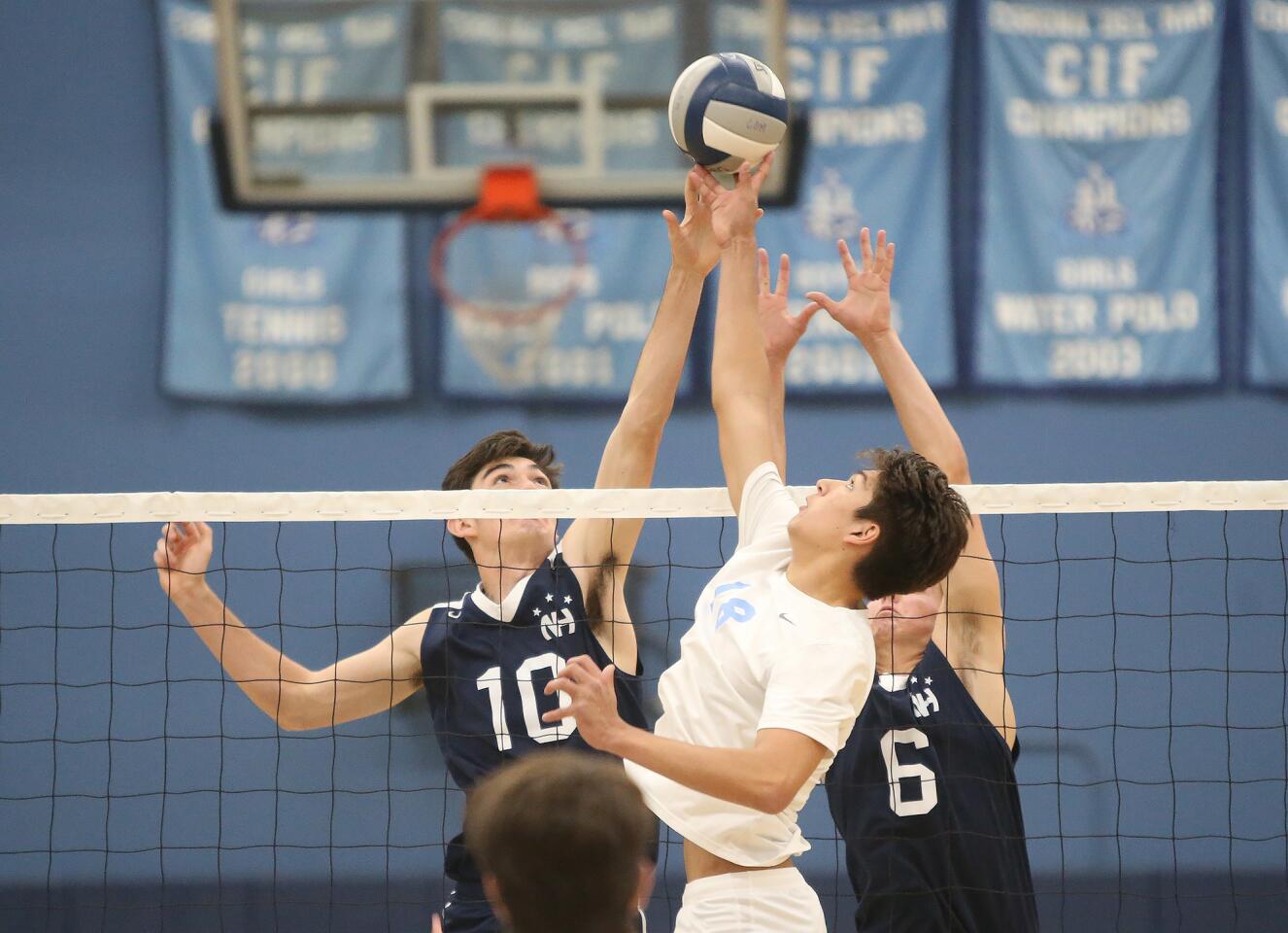 Newport Harbor's Caden Garrido (10) and Blake Ludes (6) battle for a tip with Corona Del Mar's Bryce Dvorak during second round of the Battle of the Bay boys' volleyball match in Surf League play on Wednesday.