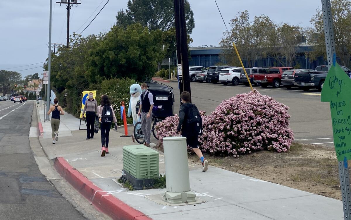 Staff members, signs and a mascot welcome Muirlands Middle School students back to onsite learning April 12.