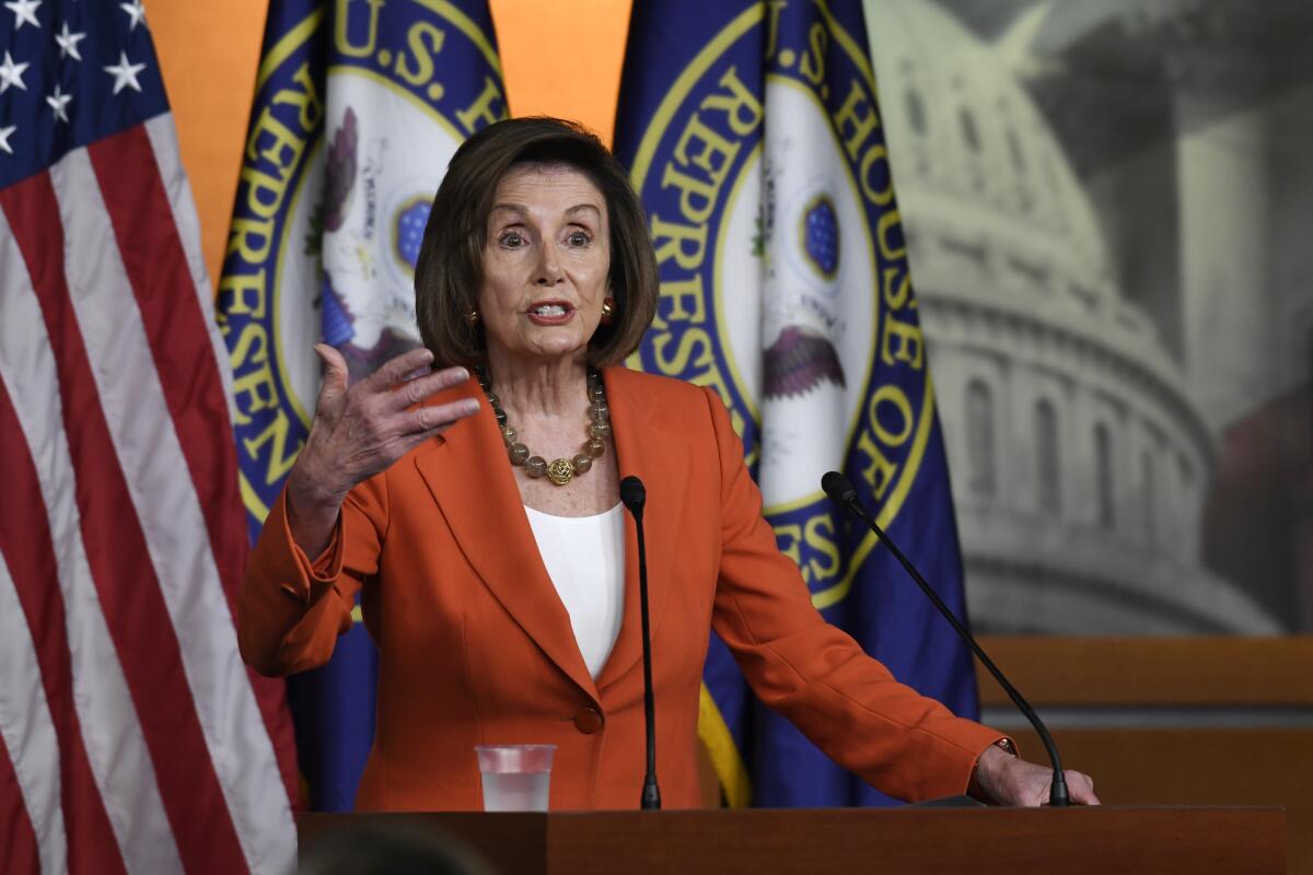 House Speaker Nancy Pelosi gestures at a microphone.