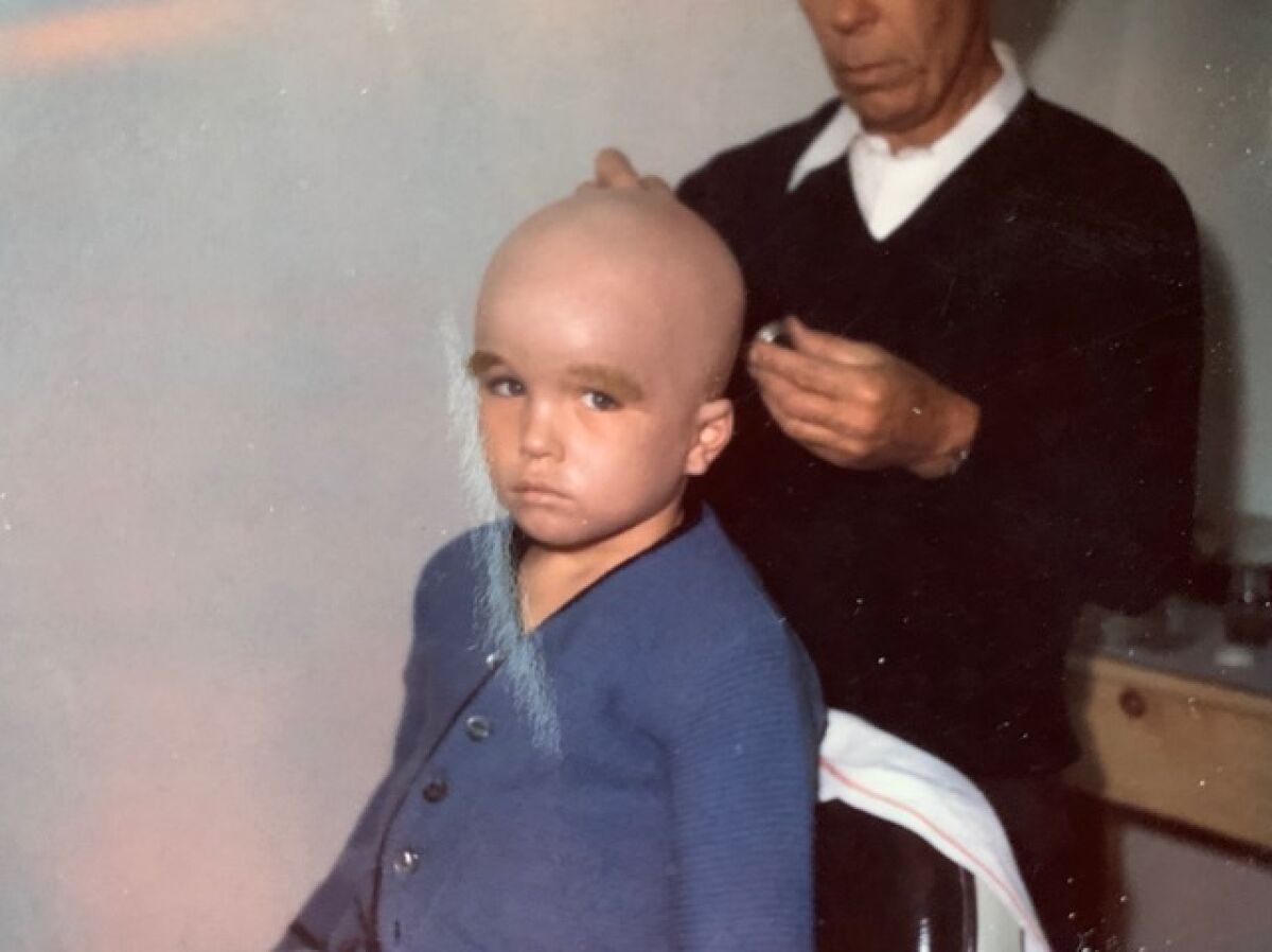 A makeup artist applies a bald cap to a young Clint Howard.