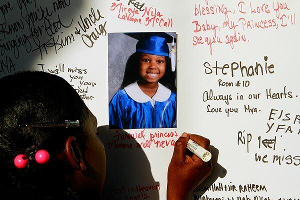 Tina Carter writes a message on a poster memorializing her daughter, Mireya Nila McCall, pictured at her kindergarten graduation. See full story