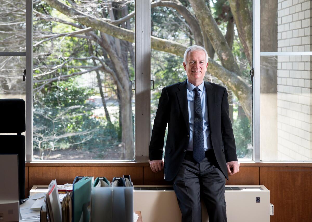 Robert Eskildsen, the vice president for academic affairs at ICU, poses for a photograph leaning against a large window 