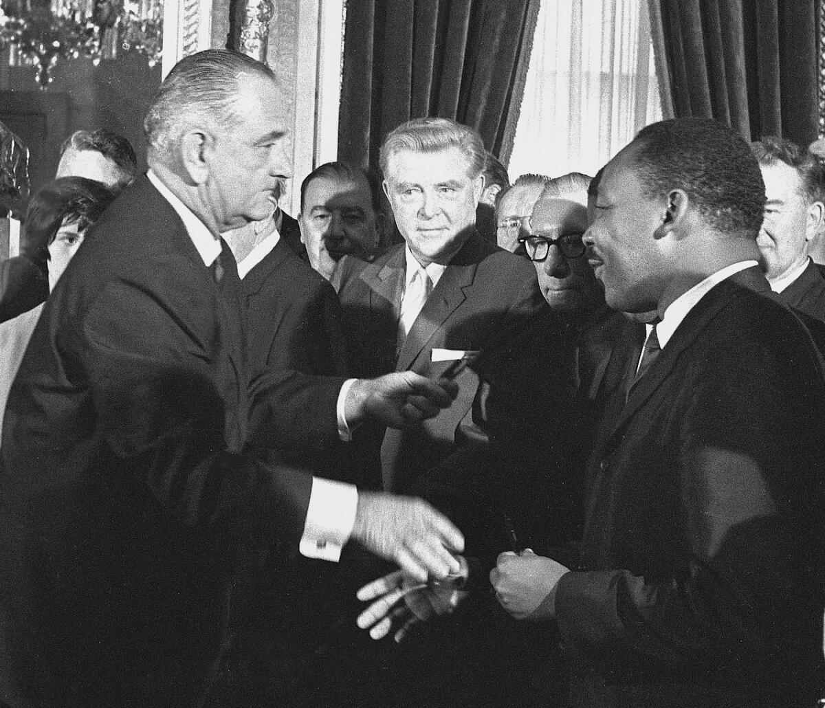 President Lyndon B. Johnson shakes hands with the Rev. Martin Luther King Jr. after signing the Voting Rights Act.