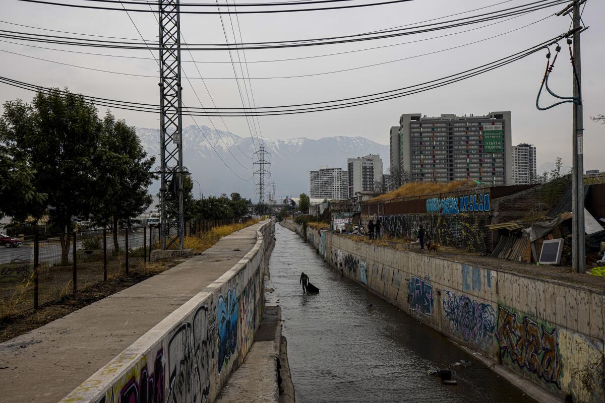 A homeless Chilean man collects items, such as metal, from the El Zanjón de la Aguada water canal.