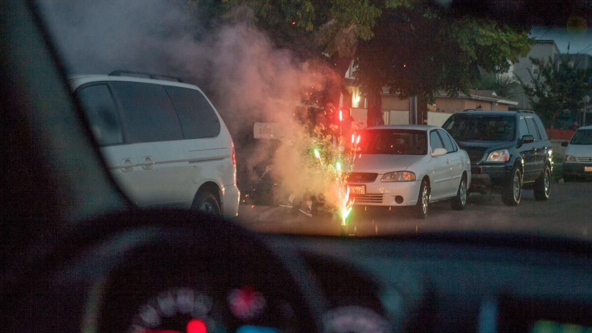 Seen from Officer Trevor Jones' patrol car, "safe and sane" legal fireworks burn on the side of a Costa Mesa street on July 4.