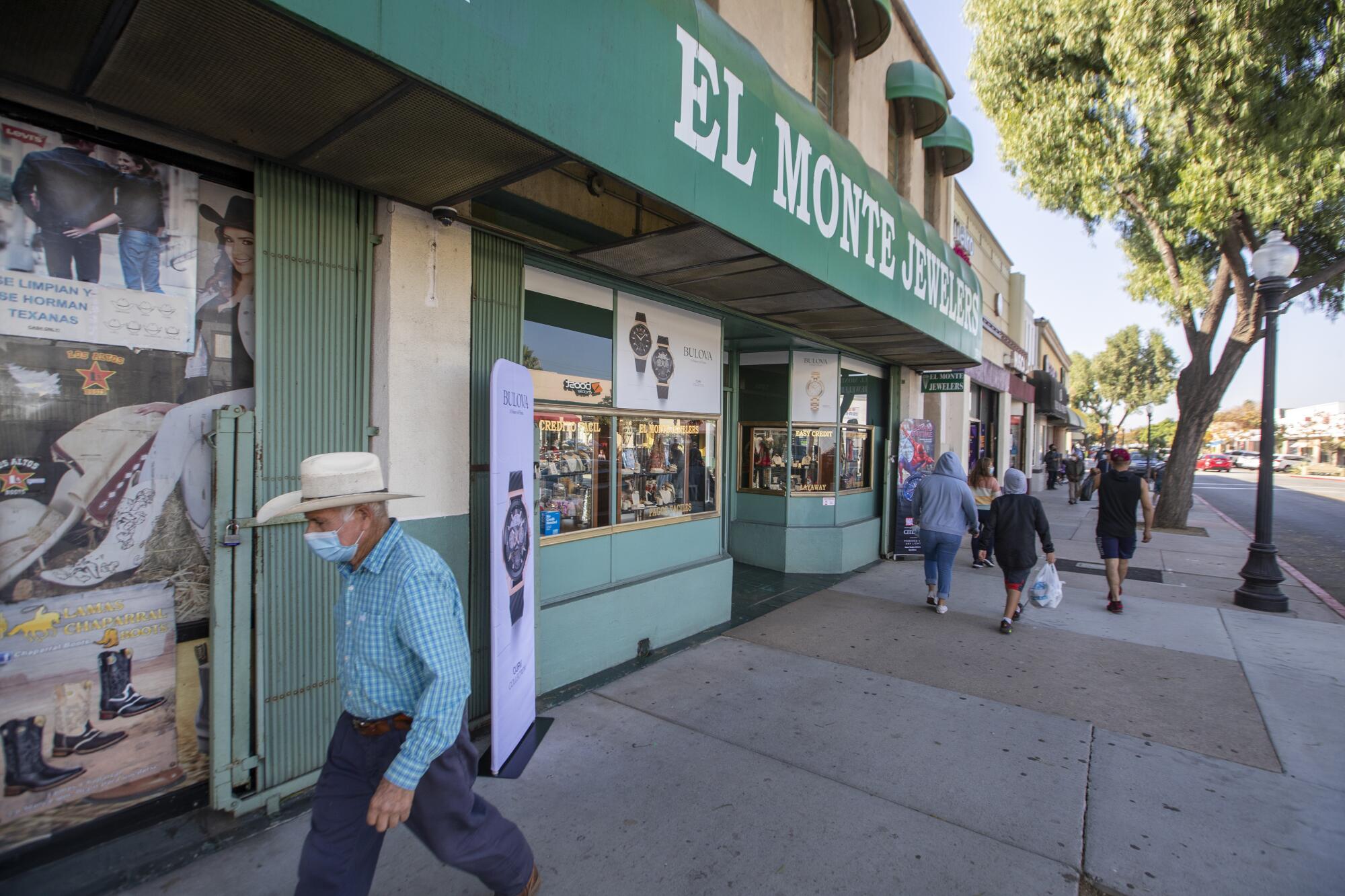 Los peatones caminan por Main Street, en El Monte, donde muchos negocios luchan por permanecer abiertos.