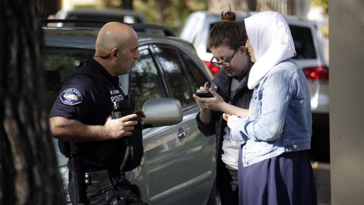 Un agente de la policia de Redlands, toma el testimonio de Rhian Beutler, al centro y de Ikrim, quien es musulmana, luego de reportar repetidas amenazas en contra de Ikrim, por parte de un automovilista.