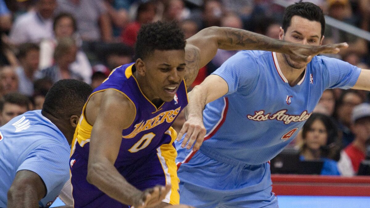 Lakers forward Nick Young (0) is tripped by Clippers forward Glen Davis, left, after getting past Davis and guard J.J. Redick.