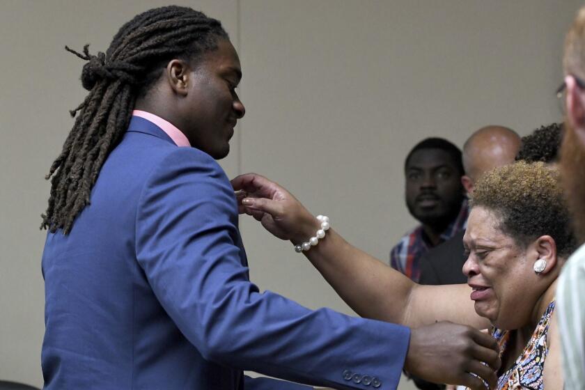 A.J. Johnson reaches to hug a family member after a jury acquitted both Johnson and Michael Williams on aggravated rape charges Friday, July 27, 2018, in Knoxville, Tenn. Johnson and Williams were indicted on February 2015 after a woman said both men raped her during a party at Johnson's apartment in the early morning hours of Nov. 16, 2014. Johnson and Williams were suspended from the team less than 48 hours after the party and never played for Tennessee again. (Michael Patrick/Knoxville News Sentinel via AP)