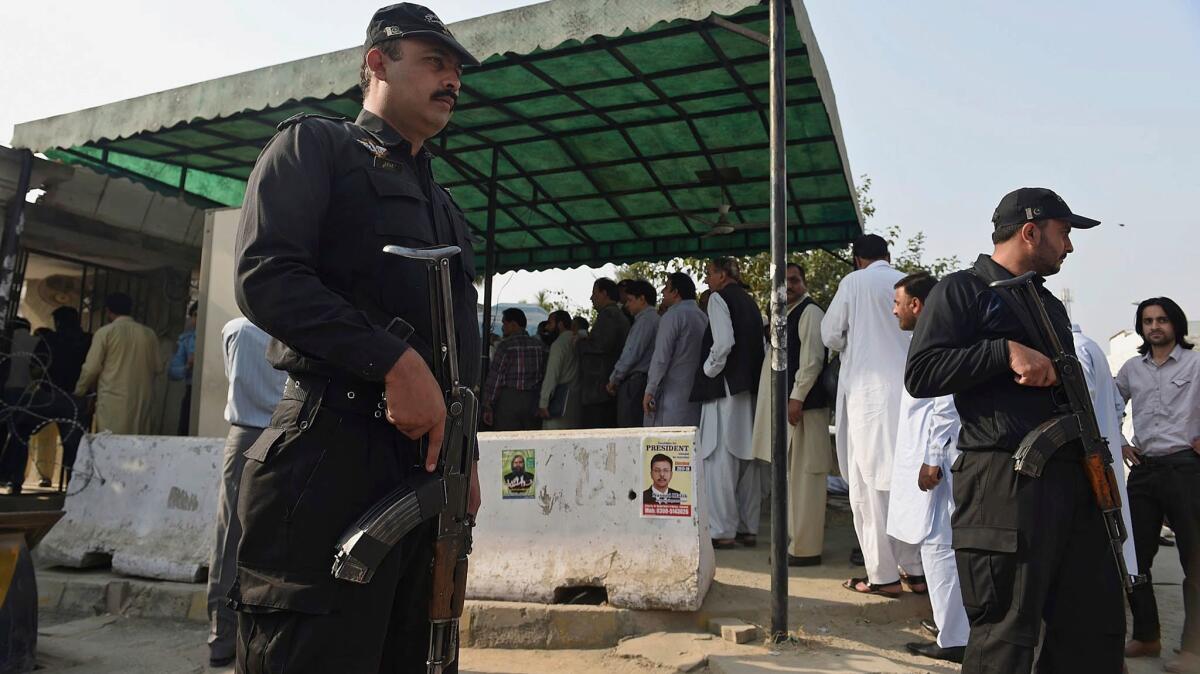 Police commandos stand guard while people line up for a security check at the entrance to a courthouse in Islamabad, Pakistan, on Oct. 31.