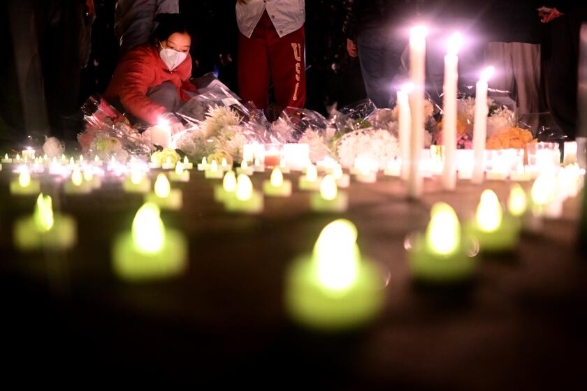 Los Angeles, California November 29, 2022-A woman lights a candle during a vigil for victims who suffer under China’s stringent lockdown in Urumqi and COVID victims on the campus of USC Tuesday night. (Wally Skalij/Los Angeles Times)