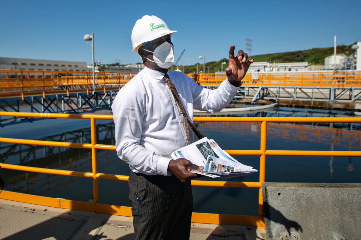 A man in a hardhat stands beside a large tank of water