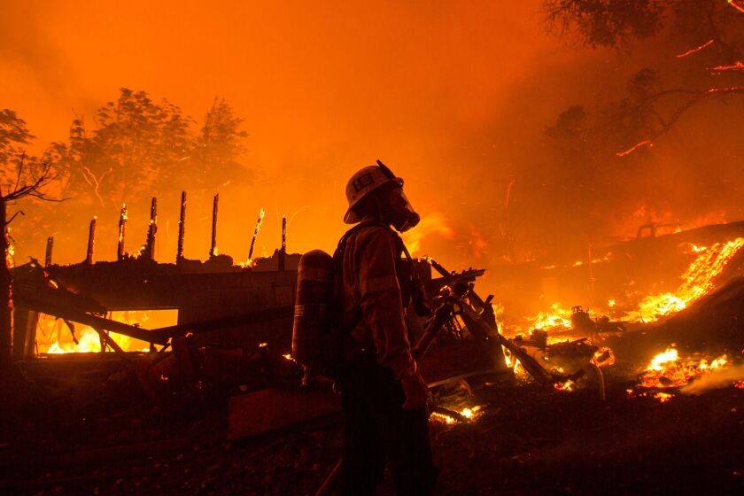 A firefighter watches the Lake Hughes fire destroy a home in Angeles National Forest on Wednesday.