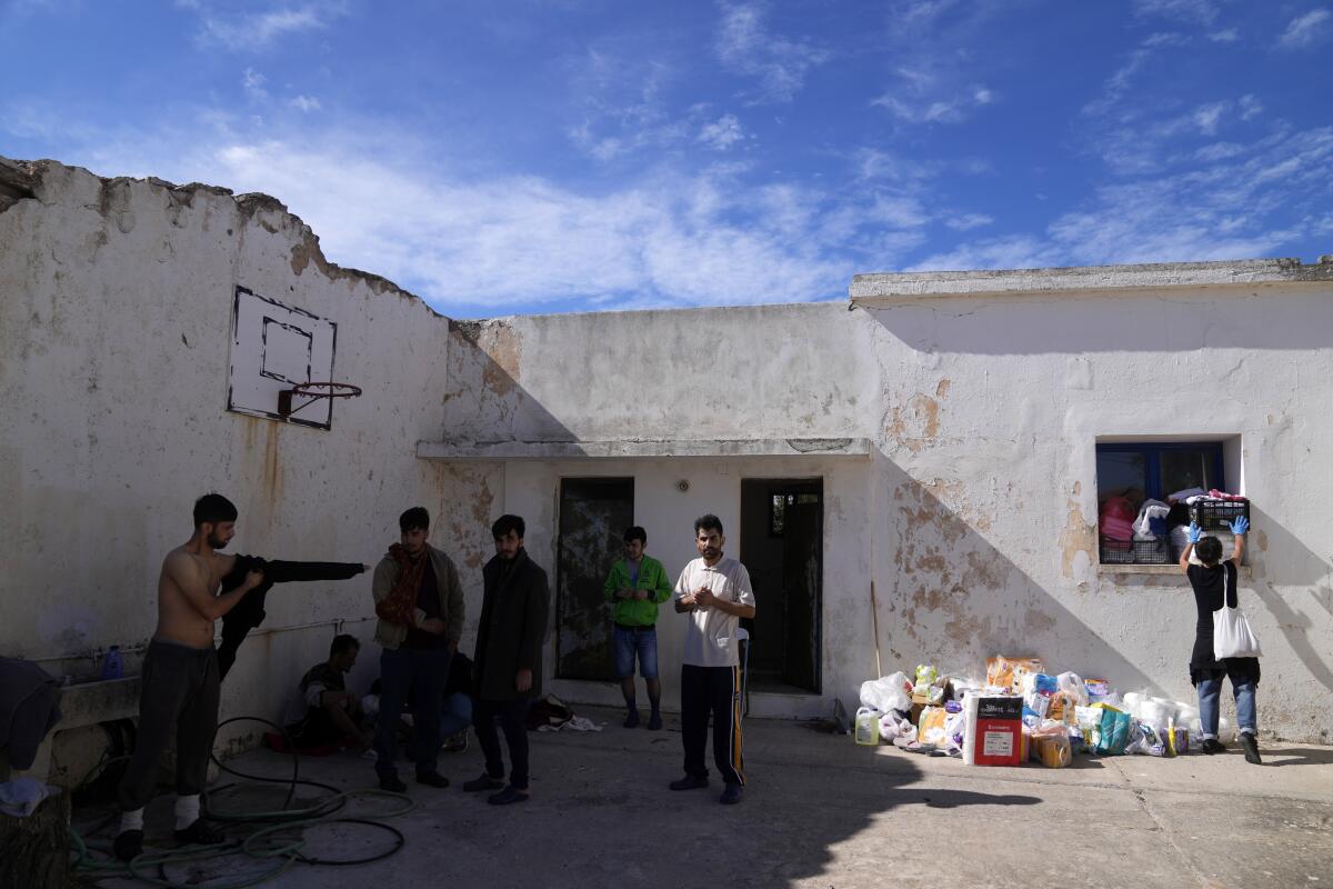 Migrants, most of them from Afghanistan, gather at an old school used as a temporary shelter on the island of Kythira, southern Greece, Thursday, Oct. 6, 2022. Bodies floated amid splintered wreckage in the wind-tossed waters off a Greek island Thursday as the death toll from the separate sinkings of two migrant boats rose to 22, with many still missing. (AP Photo/Thanassis Stavrakis)