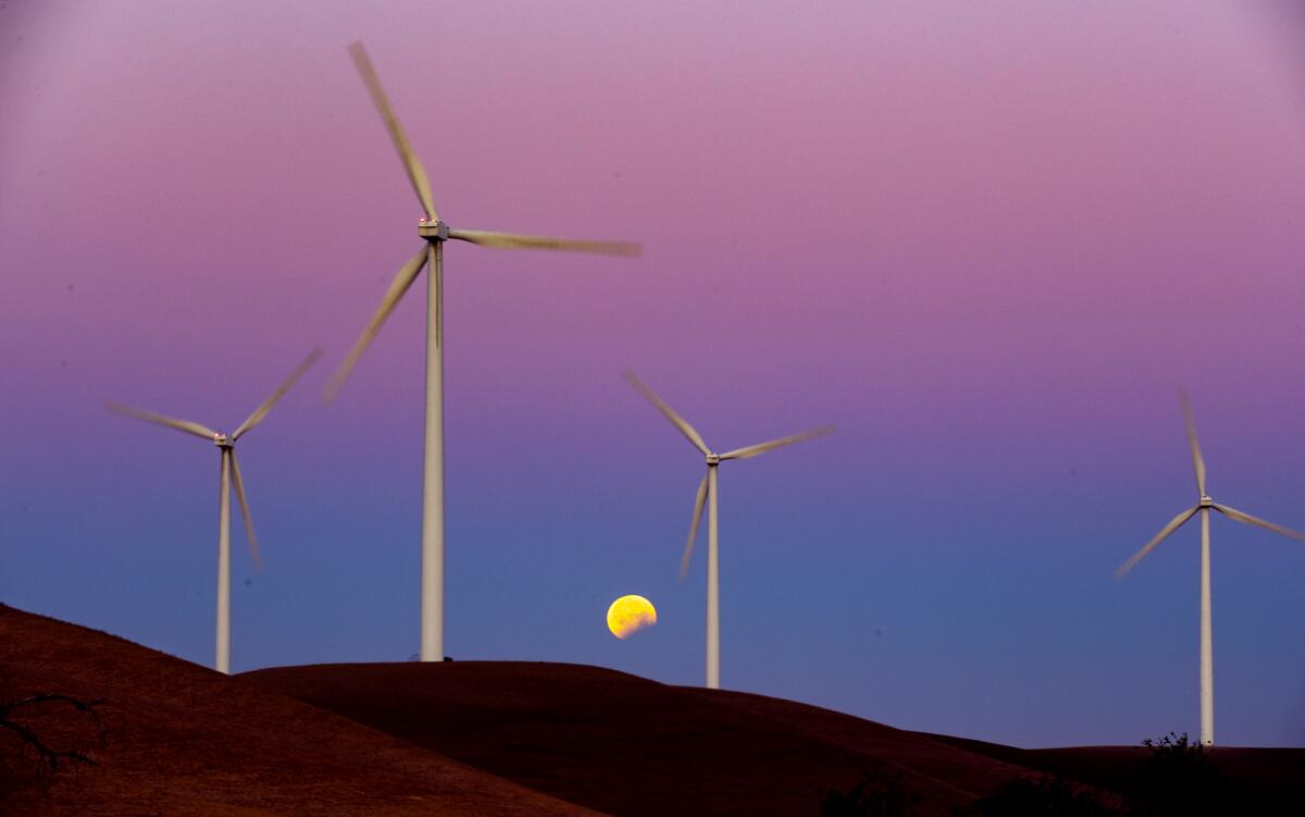 Turbines spin as the Blood Moon lunar eclipse sets behind the towers on the Shiloh II wind farm in the Montezuma Hills 