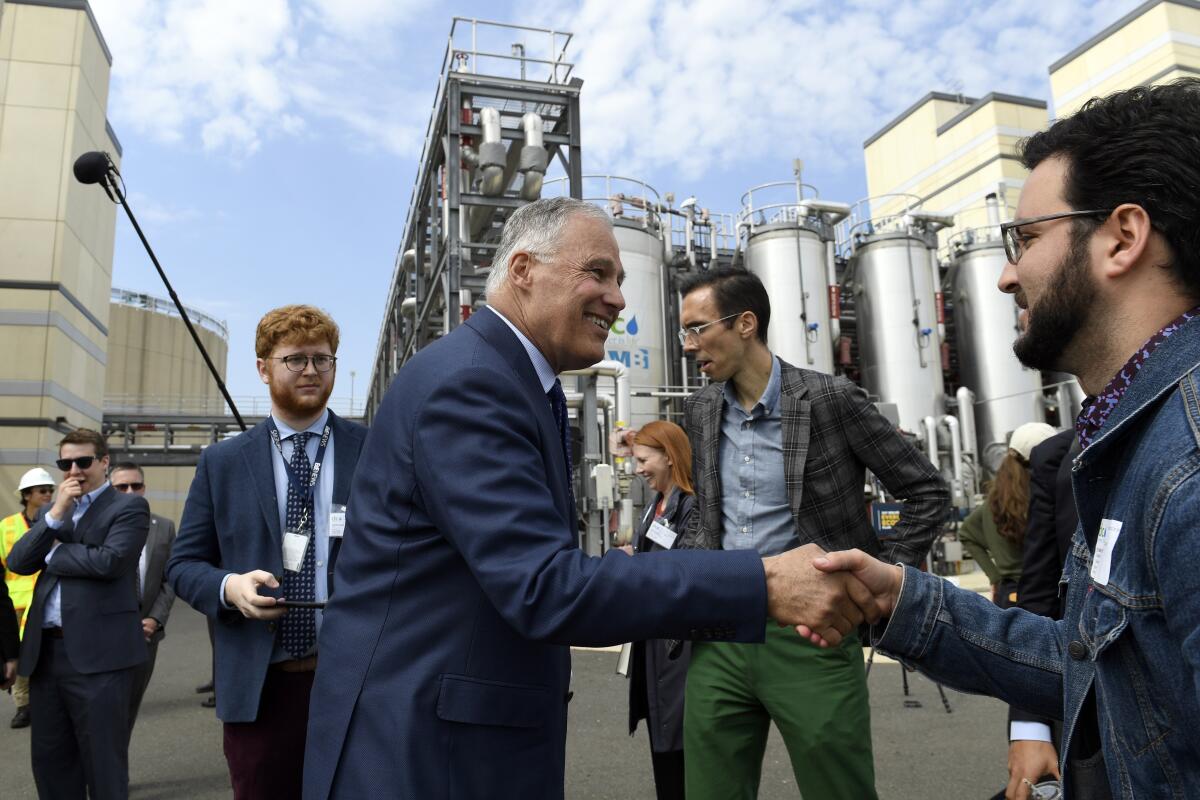 Washington Gov. Jay Inslee, center, greets workers during a tour of a wastewater treatment plant.