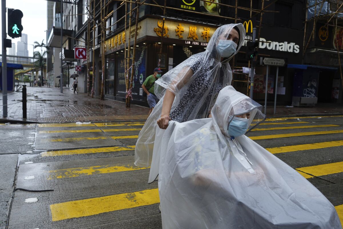 People make their way on an empty street as Typhoon Kompasu passes in Hong Kong Wednesday, Oct. 13, 2021. Hong Kong suspended classes, stock market trading and government services as the typhoon passed south of the city Wednesday. (AP Photo/Vincent Yu)