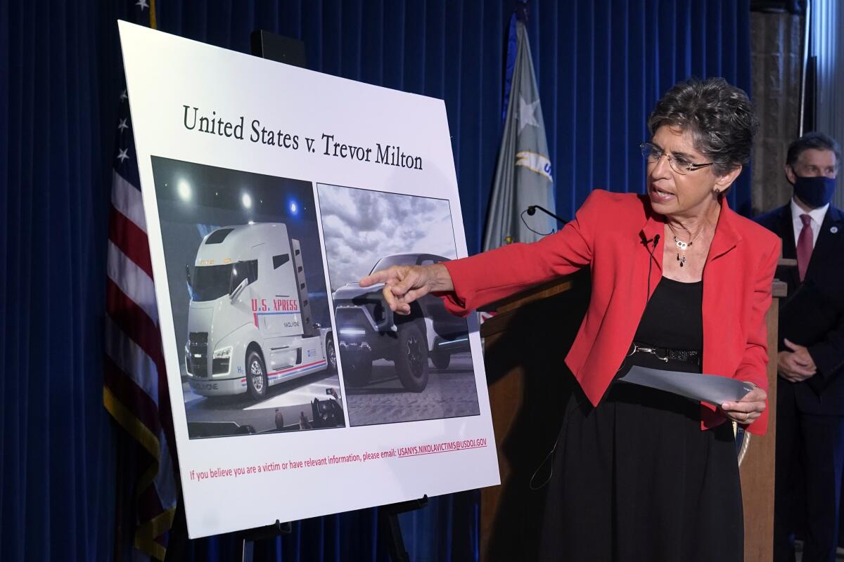 A woman points to a poster displayed on an easel at a news conference