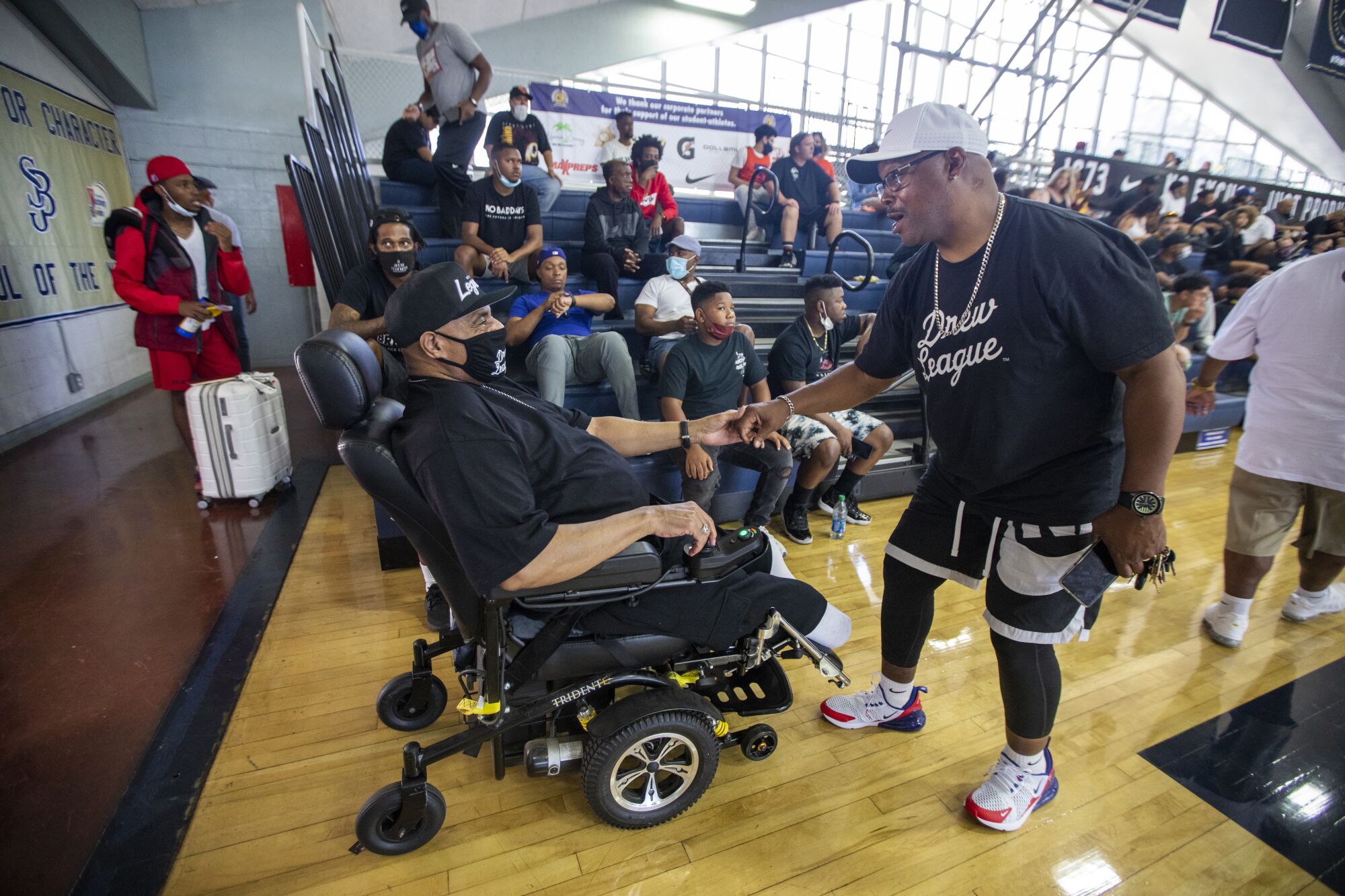 Friend greets Bill Crawford as he arrives in his wheelchair at a high school gymnasium on June 19.