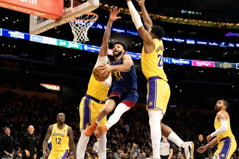 LOS ANGELES, CA - APRIL 25, 2024: Denver Nuggets guard Jamal Murray (27) splits defenders Los Angeles Lakers forward Anthony Davis (3) and Los Angeles Lakers forward Rui Hachimura (28) to make a pass under the basket in the fourth quarter of Denver's Game 3 win in the first round of the NBA playoffs at Crypto.com Arena on April 25, 2024 in Los Angeles, CA.(Gina Ferazzi / Los Angeles Times)
