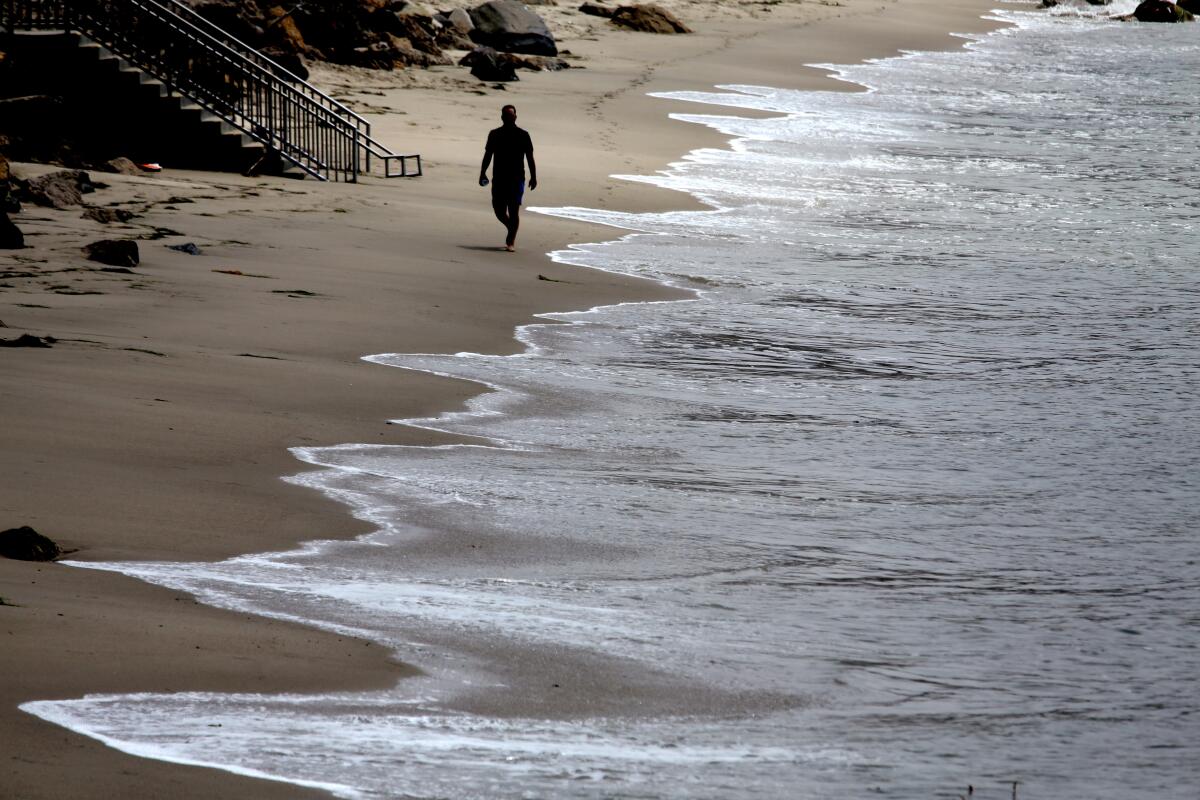 A person walks along the beach near the Malibu Pier. 