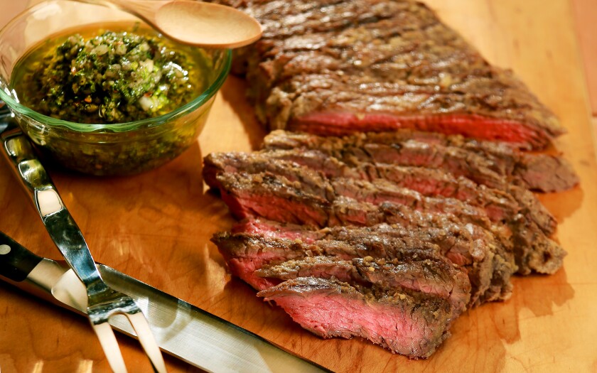 Sliced skirt steak with a bowl of chimichurri sauce