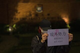 Una manifestante sostiene un cartel con los mensajes "Fuerzas extranjeras no, fuerzas internas" y "El abuso del poder del gobierno hunde a la gente en la miseria y el sufrimiento" durante un encuentro en la Universidad de Hong Kong, en Hong Kong, el martes 29 de noviembre de 2022. (AP Foto/Bertha Wang)