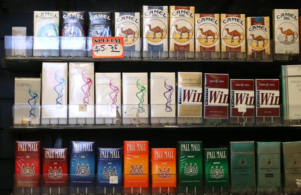 Cigarette brands manufactured by Reynolds American are displayed at a tobacco shop in San Francisco. The tobacco giant agreed to merge with Lorillard Inc. in a $27.4-billion deal.