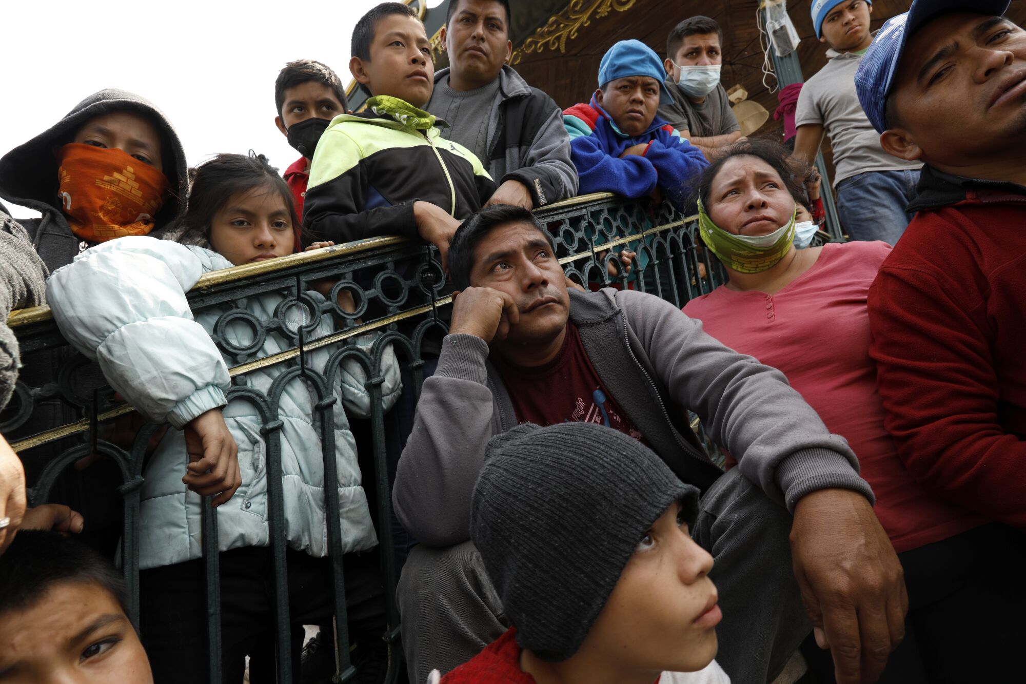 Men, women and children crowd around a railing.