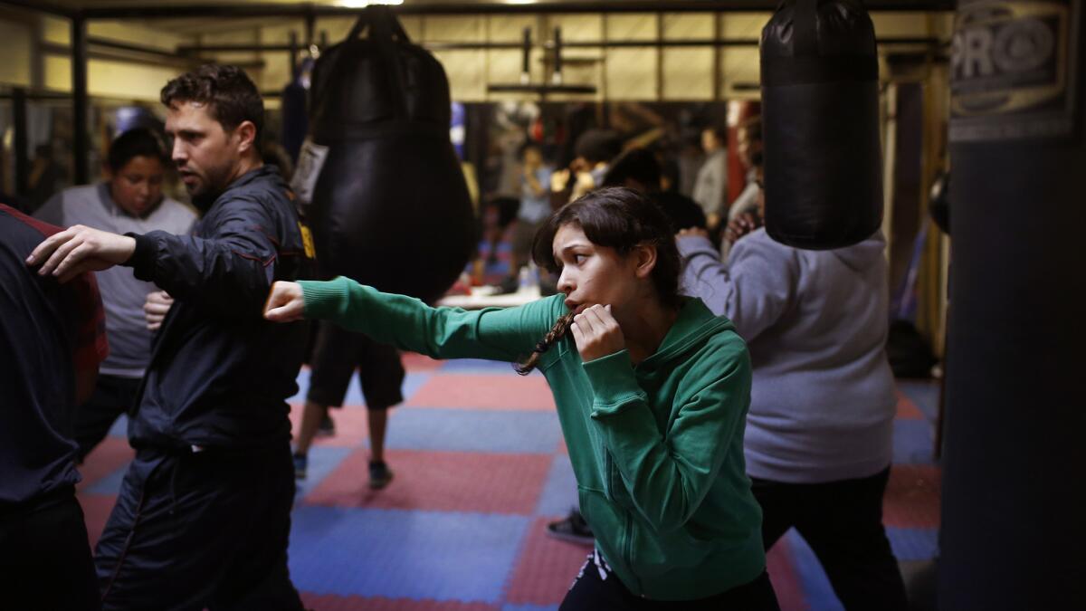 Gina Garcia, 13, works on her boxing technique while coach Jeff Sacha, 29, assists another boxer in the gym.