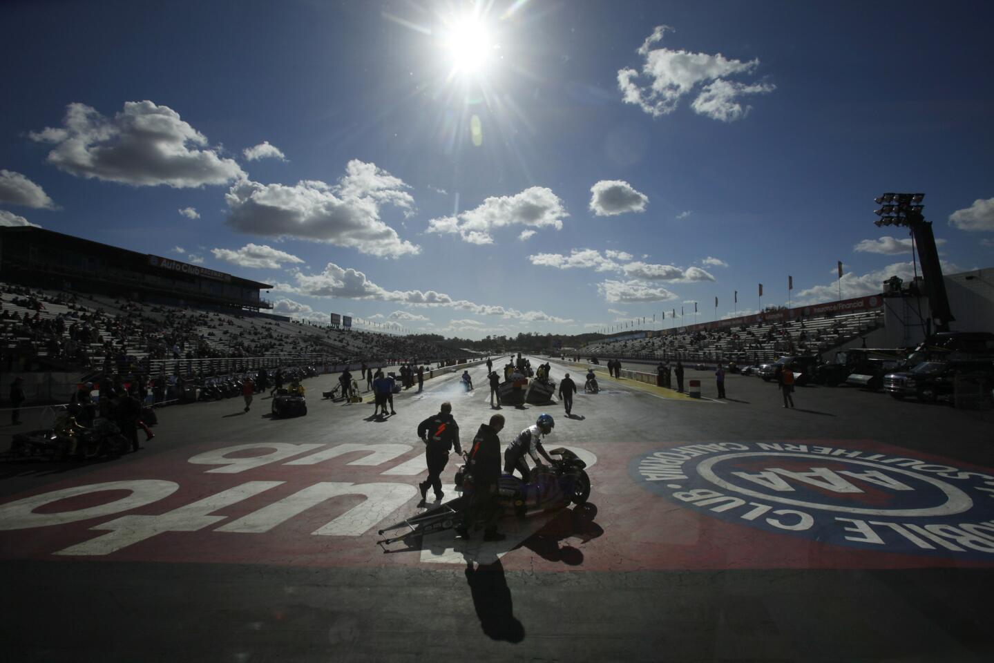 The Pro Stock Motorcycle competitors walk their bikes to the starting line during one of the qaulifying runs at the 48th Annual NHRA Auto Club Finals underway at the Auto Club Raceway in Pomona.