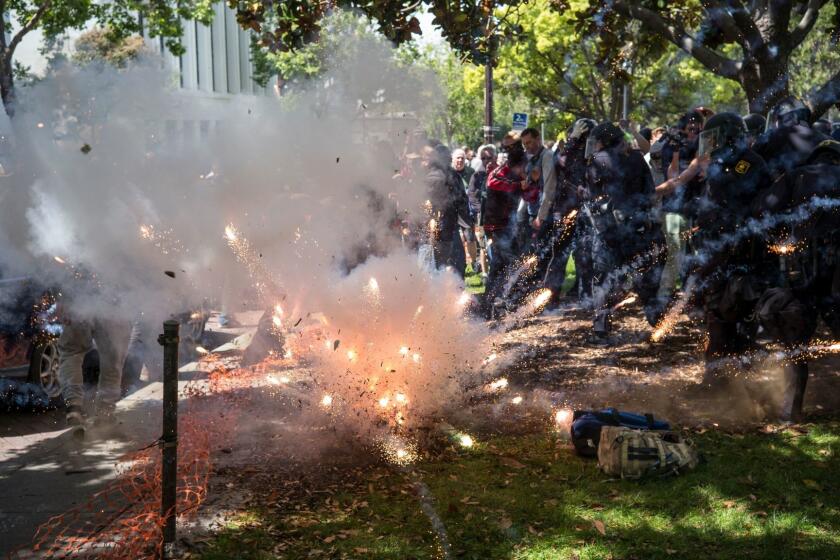 APRIL 15, 2017 BERKELEY, CA A firework thrown by someone in the crowd explodes at the feet of police and supporters of President Donald Trump as they clash with protesters at a rally at Civic Center Park organized by the Trump supporters. Photo by David Butow/for the Times