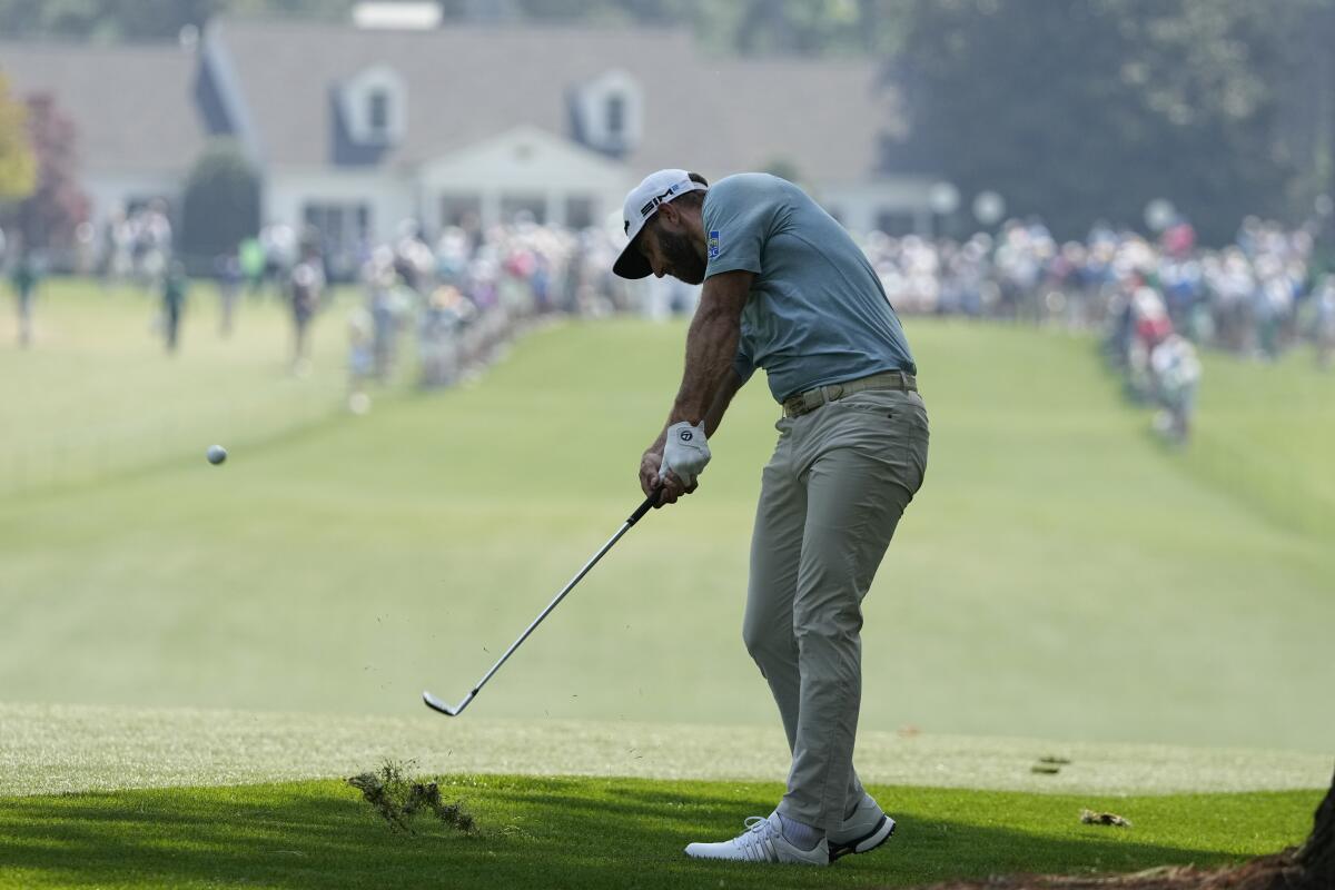 Dustin Johnson digs out a divot hitting from the first fairway 
