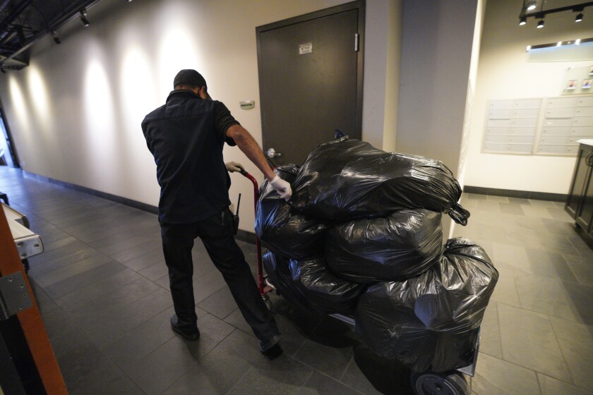 Marco Duarte, a maintenance worker at the Parkloft Condominiums, takes trash bags to the dumpsters. 