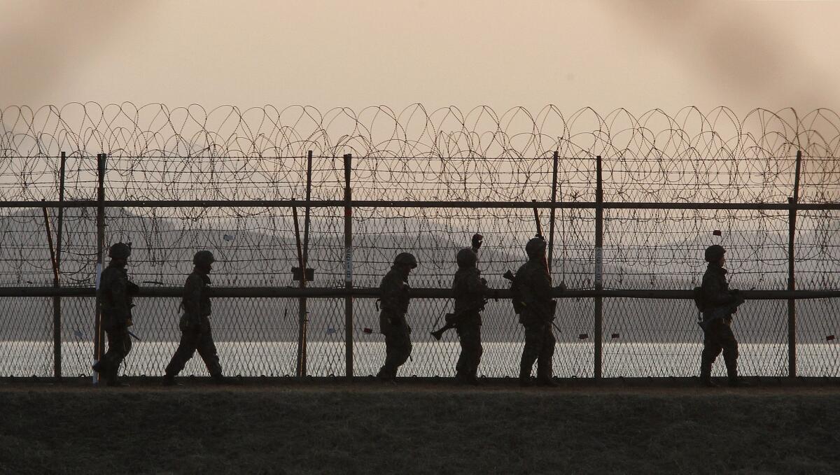 South Korean soldiers patrol along a barbed-wire fence near the border village of Panmunjom, in the demilitarized zone between North and South Korea, on March 26, 2013.