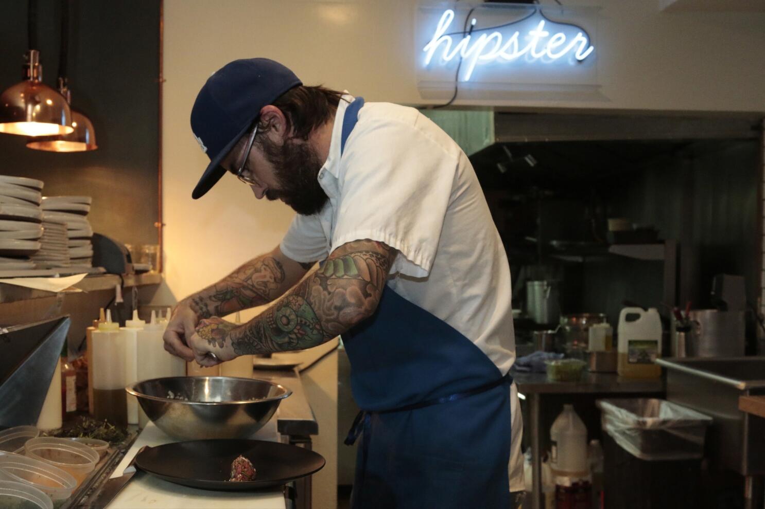 The chef cooks small octopus on a metal frying pan at the