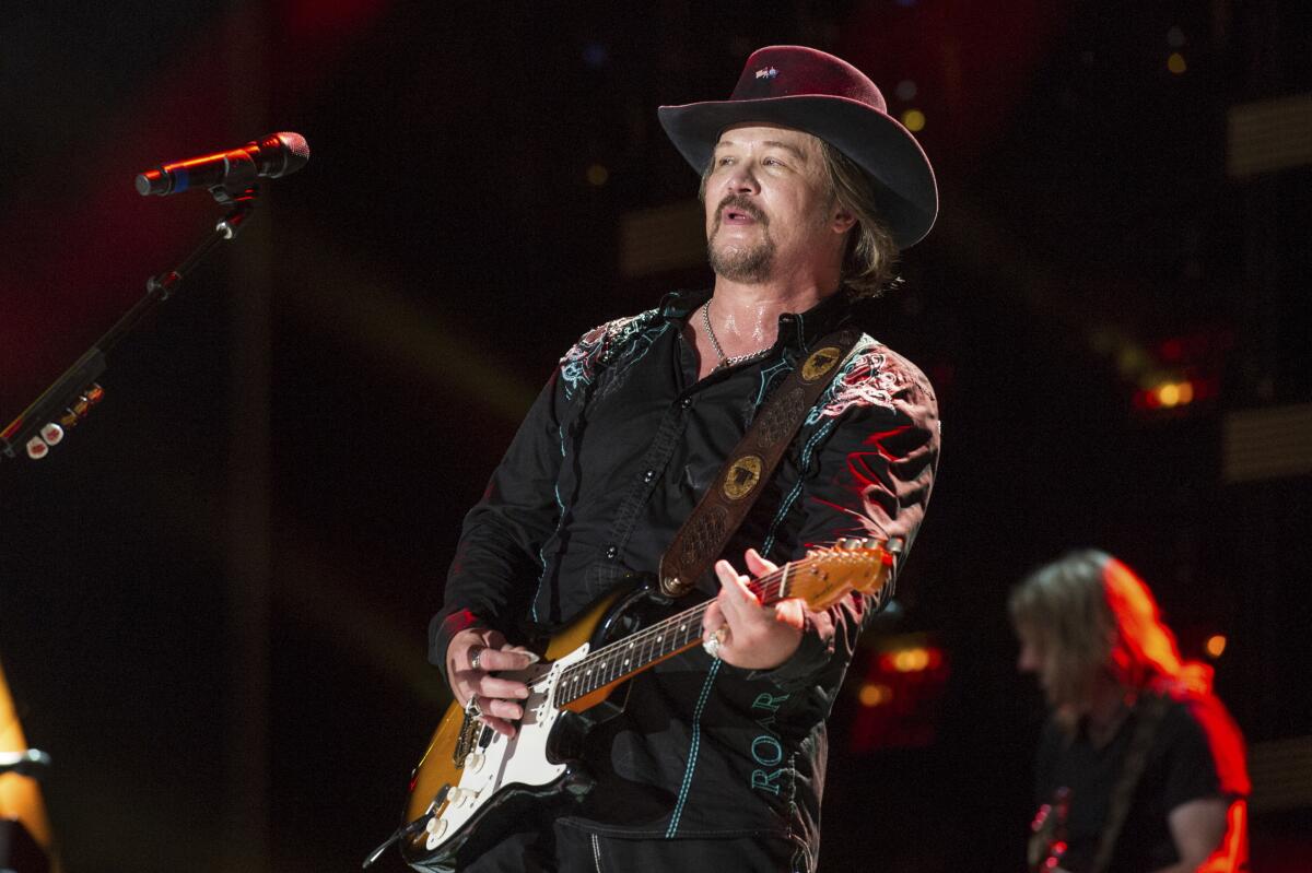 A man in a cowboy hat playing a guitar onstage