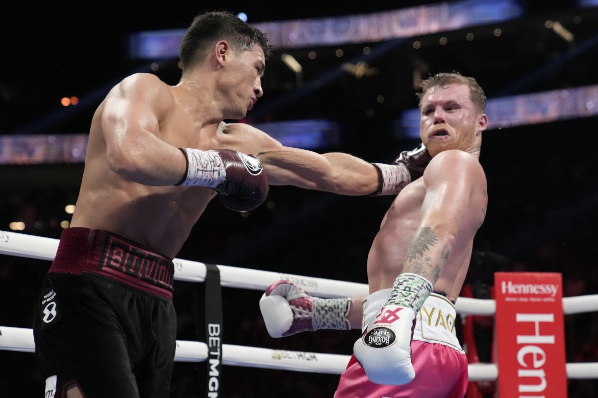 Dmitry Bivol, left, throws a punch at Canelo Álvarez during their light heavyweight fight Saturday.