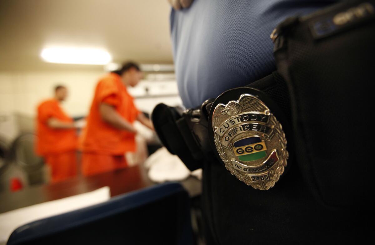 A closeup of a badge on a guard watching over detainees