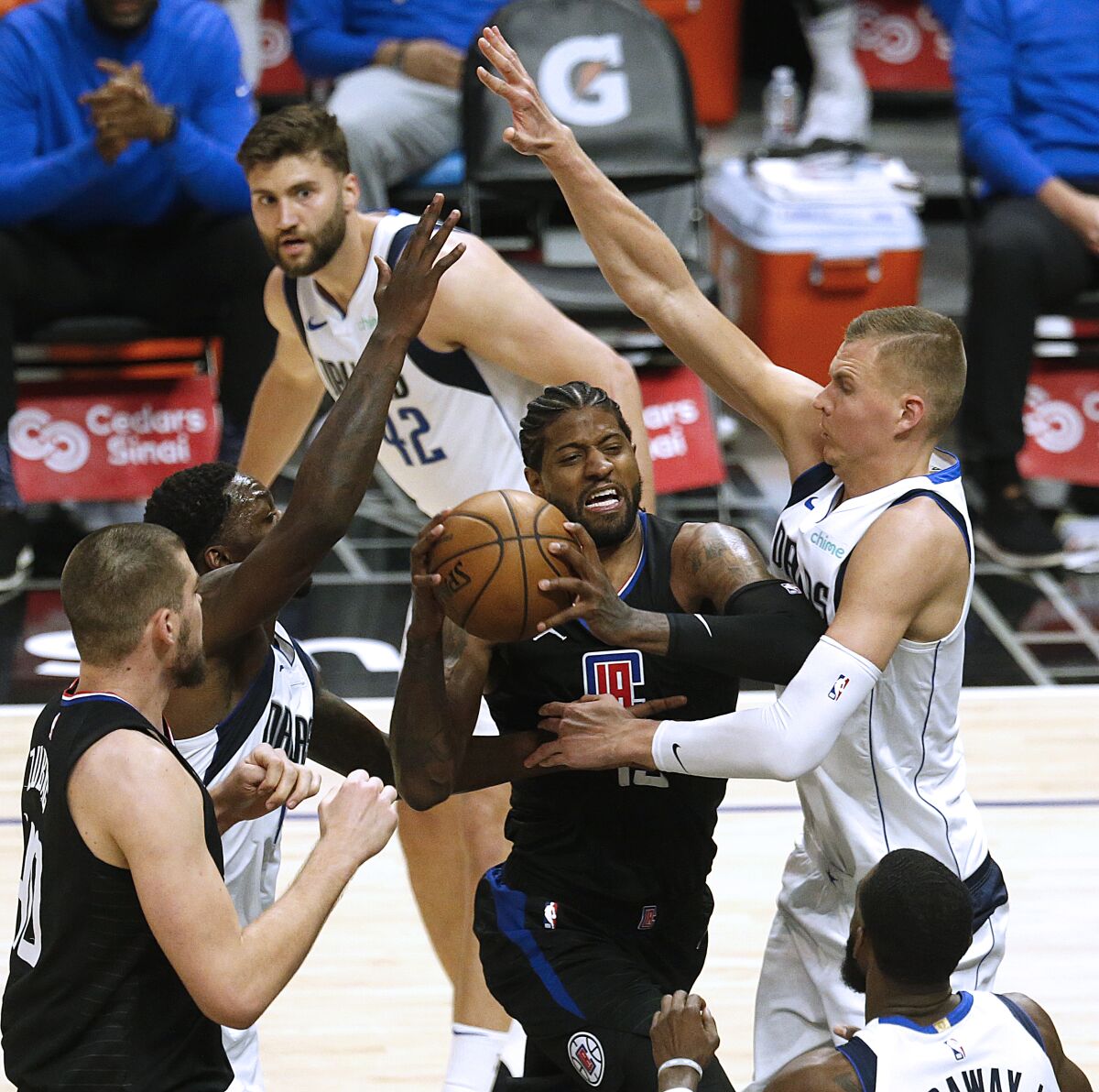 Clippers guard Paul George is defended by Dallas Mavericks forward Dorian Finney-Smith and center Kristaps Porzingis.