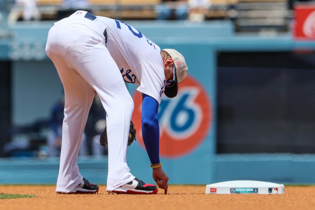 Dodgers infielder Miguel Rojas scratches a message in the dirt near second base at Dodger Stadium on May 18.