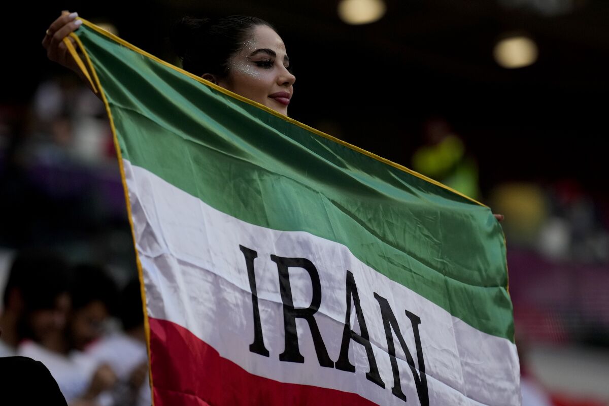 A soccer fan holds a flag from Iran prior to the World Cup group B soccer match between Wales and Iran, at the Ahmad Bin Ali Stadium in Al Rayyan , Qatar, Friday, Nov. 25, 2022. (AP Photo/Francisco Seco)