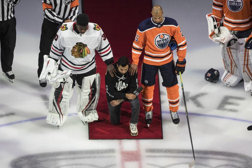Minnesota Wild's Matt Dumba takes a knee during the national anthem flanked by Edmonton Oilers' Darnell Nurse, right, and Chicago Blackhawks' Malcolm Subban before an NHL hockey Stanley Cup playoff game in Edmonton, Alberta, Saturday, Aug. 1, 2020. (Jason Franson/The Canadian Press via AP)