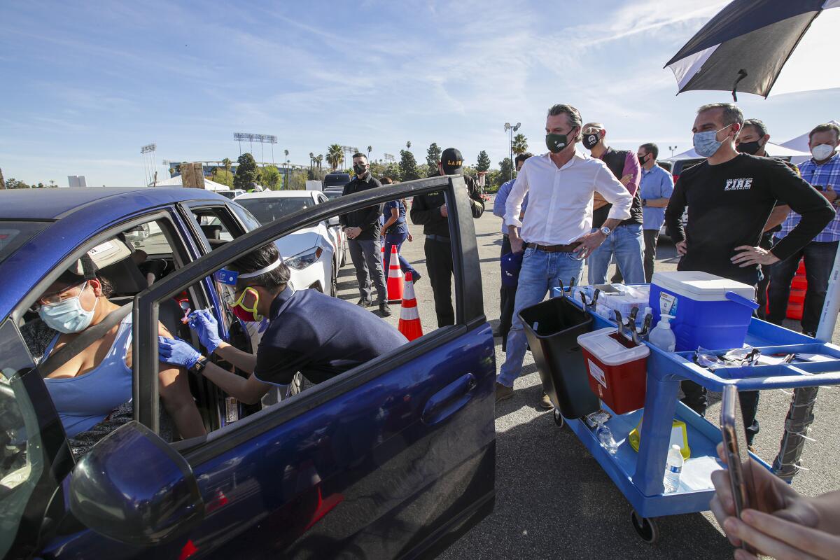 Gov. Gavin Newsom and L.A. Mayor Eric Garcetti watch people get vaccinated at Dodger Stadium on Jan. 15.